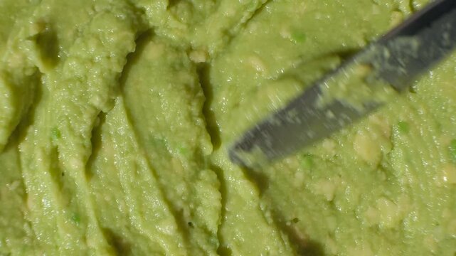 Person demonstrating the thick texture of organic delicious guacamole sauce.