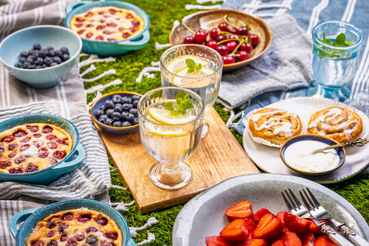 Delicious summer picnic spread with fresh fruits and baked treats on green grass