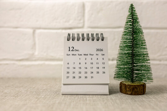 Desk calendar for December 2026 and a Christmas tree on the table.