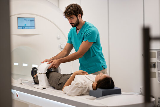 Medical technician preparing patient for knee mri scan
