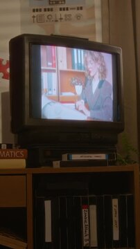 Vertical of retro CRT television displaying vintage footage of young adult Caucasian woman typing in office. Clip is ideal for nostalgia marketing campaigns or media history documentaries