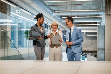 Fototapeta premium Business colleagues discussing project on tablet in modern office — Black and Caucasian professionals