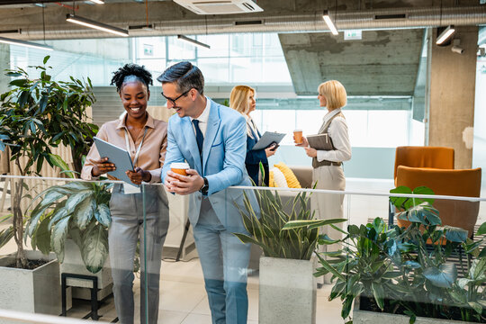 Business colleagues in modern office collaborating over tablet and coffee in open workspace