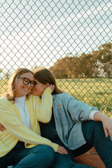 Young female couple whispering and smiling together outdoors © Cavan