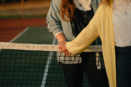 Two women holding hands over a tennis net