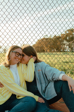 Young female couple whispering and smiling together outdoors