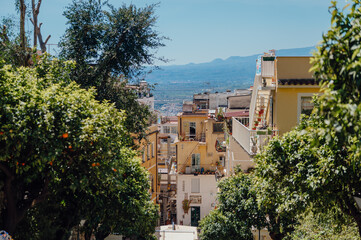 Naklejka premium Lush trees framing a sunny hillside Italian town Taormina