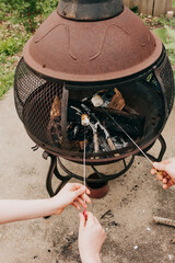Hands roasting marshmallows over an outdoor fire pit © Cavan