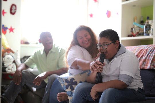 Young boy sings karaoke with his happy family at home