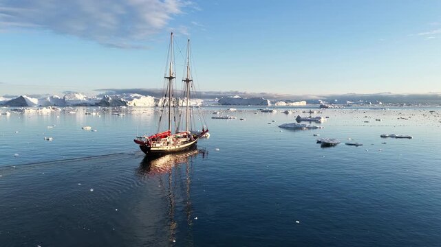 Tall ship sailing among icebergs in the arctic