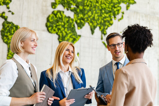 Business colleagues in a friendly meeting discussing projects in an international office with green world map