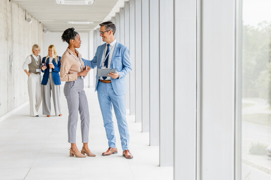 Business colleagues having a friendly conversation in a modern office corridor during a workday