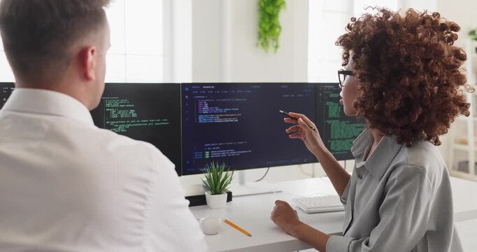 Programmers developers team coding collaboration in office. They review code on dual screens in a bright workspace to plan fixes and features. Strong teamwork and efficient coding concept.