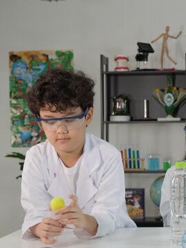 Asian Boy in Lab Coat Performing Bernoulli Principle Science Experiment