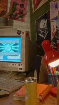 Vertical video of retro computer monitor displaying colorful visualizer on messy student desk with vintage lamp and keyboard. For nostalgic marketing campaigns and technology history documentaries