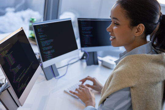 Cheerful woman programmer working with code in office