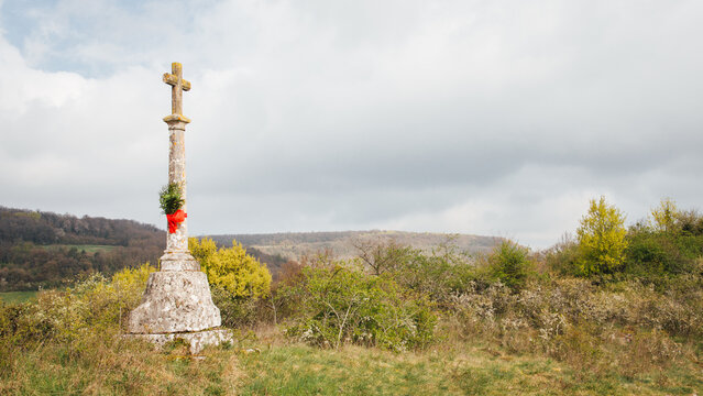 Calvaire avec un ruban rouge et du buis pour les rameaux de P&acirc;ques. Symbole chr&eacute;tien dans la campagne. Passion du Christ