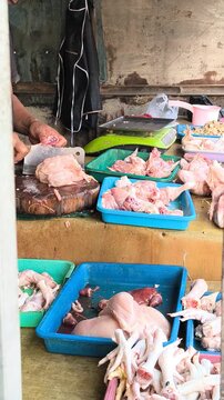 Butcher cutting fresh raw chicken at a traditional Indonesian market