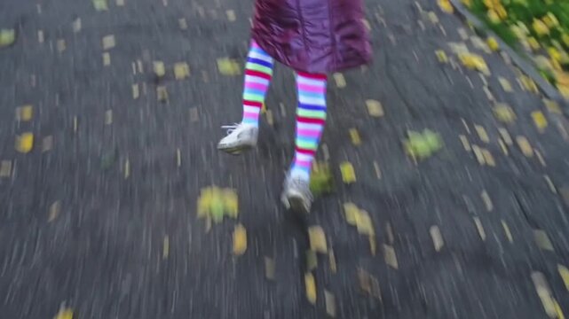 little girl jumping on asphalt in autumn park