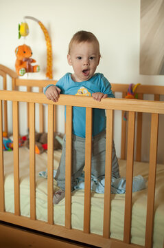 Little one stands in crib, gazing with wide-eyed wonder at the start of a bright new day