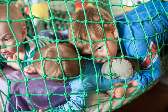 Sibling sanctuary embraced by emerald strands, three innocent brothers share a tender moment within their safe play haven at home during a sunlit day