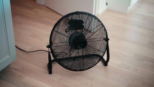 Black Electric Floor Fan Running in Apartment During European Summer Heatwave