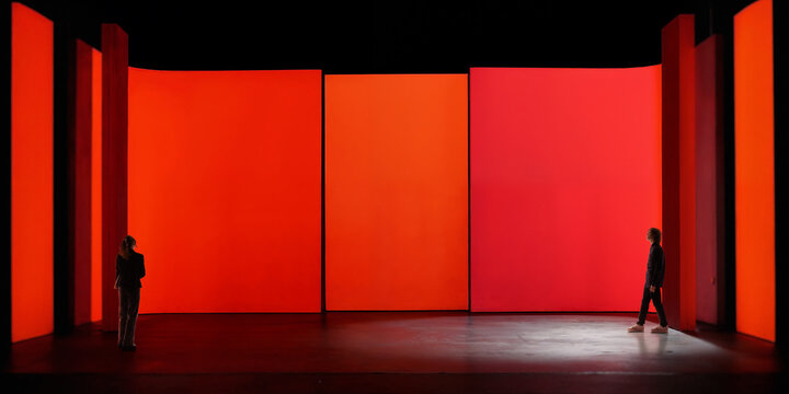 People stand inside immersive red chamber with curved digital panels, dark contrast, and wide cinematic layout. Fits virtual environments, tech branding, and XR campaigns.
