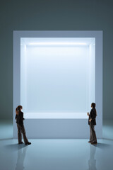 Fototapeta premium Two women stand before luminous digital portal in pale futuristic space with soft cool light, reflective floor, and centered composition. Fits digital interfaces, XR, and spatial technology campaigns.