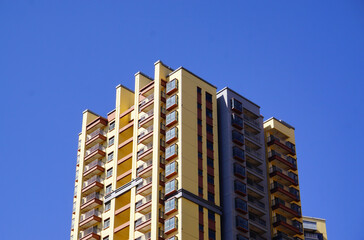 Fototapeta premium Modern High-Rise Residential Apartment Building Under Clear Blue Sky