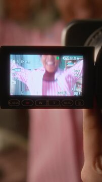 Vertical portrait of African American teenage girl smiling and dancing cheerleader routine with pompoms filmed on camcorder screen. Social media content and youth lifestyle campaigns