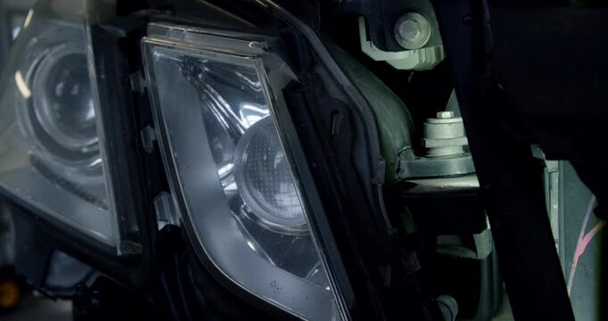 Close up shot of a modern car headlight assembly and internal wiring during an auto body repair