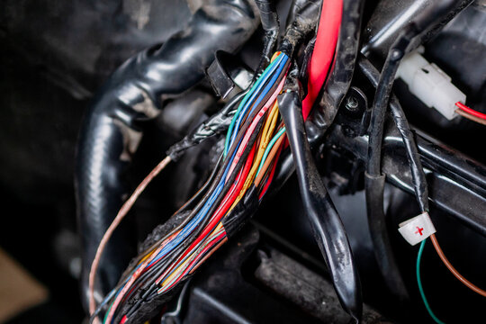 Close up of colorful electrical wires and car loom harness under vehicle hood, automotive electricity repair and maintenance concept