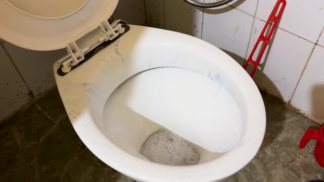 pouring toilet cleaner into washroom commode for deep cleaning and hygiene maintenance