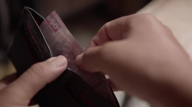 Close up of a person removing a banknote from a wallet, illustrating cash payment, personal finance and everyday money handling activities