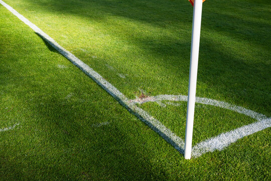 Empty corner kick arc and flag pole on a sunny professional soccer pitch.