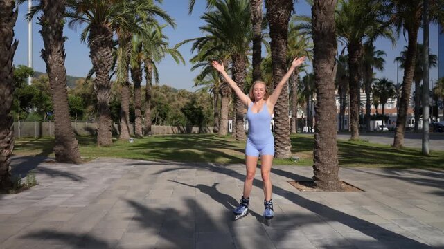 Young woman roller skating in a city park with palm trees