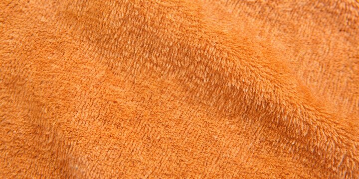 Orange terry cloth towel texture background with soft wavy folds