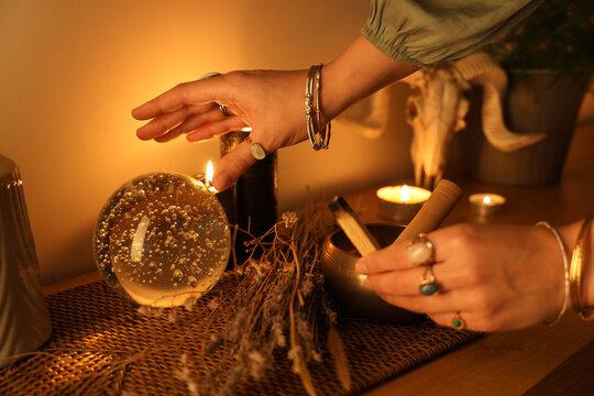 Woman with palo santo and crystal ball at home, closeup
