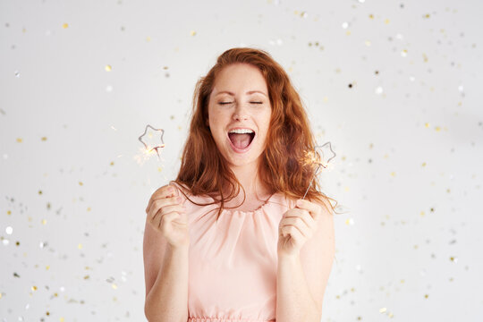 Portrait of shouting young woman with two sparklers