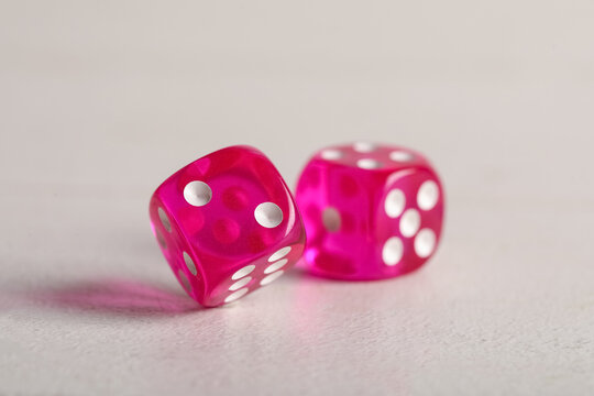 Pink game dices on white wooden background