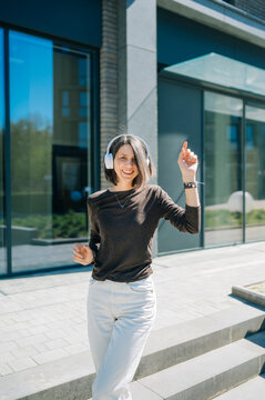 Smiling music lover dancing with headphones in the city