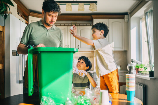 Father and child sorting plastic waste in kitchen