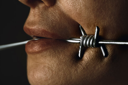 Mouth restricted by barbed wire representing censorship and control