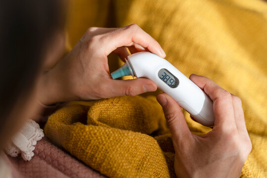 Woman checking temperature with thermometer at home