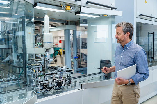 Engineer inspecting industrial robot in modern automated factory