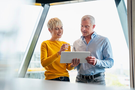 Colleagues discussing business strategy on tablet at the office