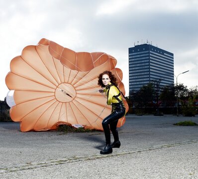 Skydiver pulling an orange parachute in the city