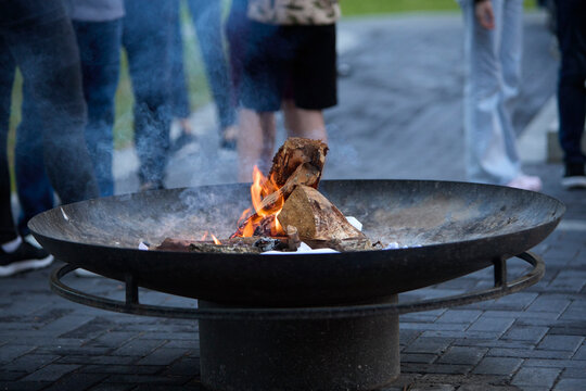 Lighting a campfire with a portable gas burner outdoors. Close-up of a person using a gas torch to ignite firewood for a cozy outdoor fire.