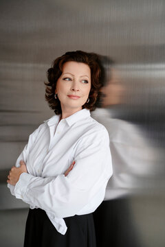 Confident businesswoman leaning on metal wall at indoor workspace