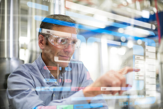 Man wearing safety goggles using transparent touchscreen device